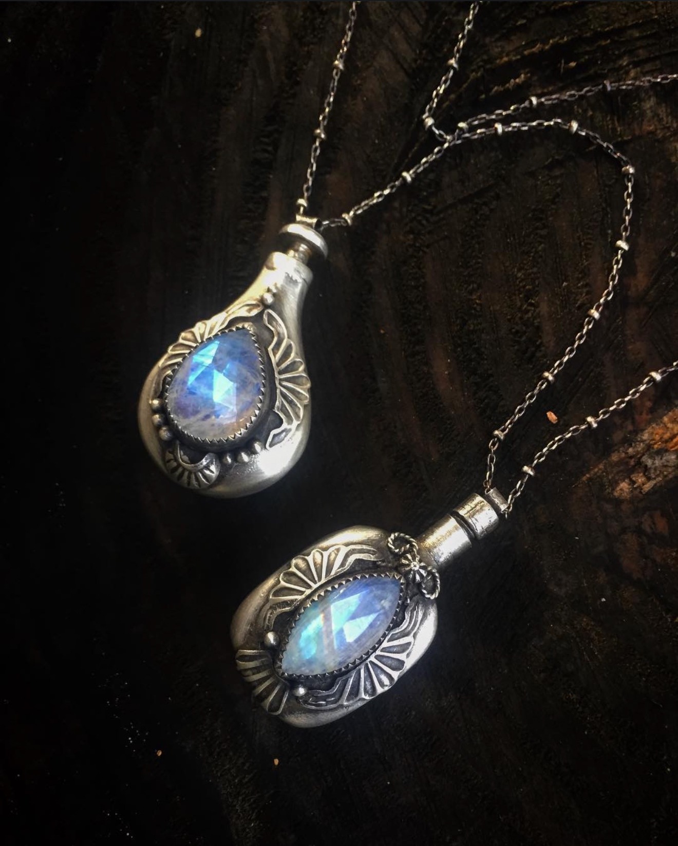 Two moonstone perfume phial pendants on dark wood — the Moonstone Phials, 2018