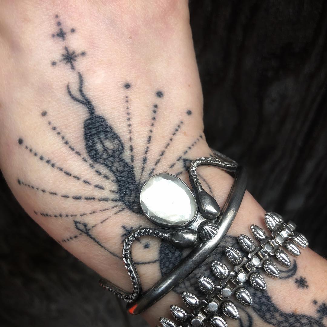Jenna's tattooed wrist wearing the sterling serpent cuff